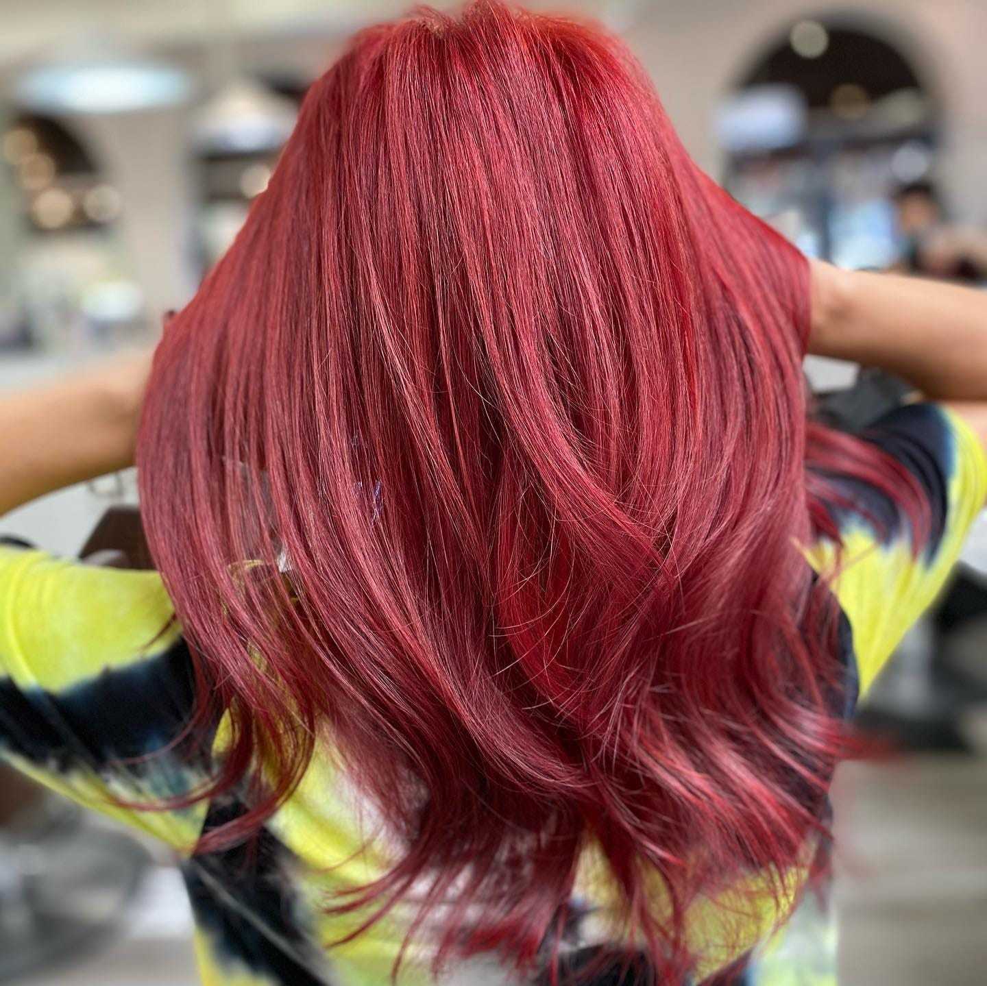 Woman with long, vibrant red hair in a salon setting.