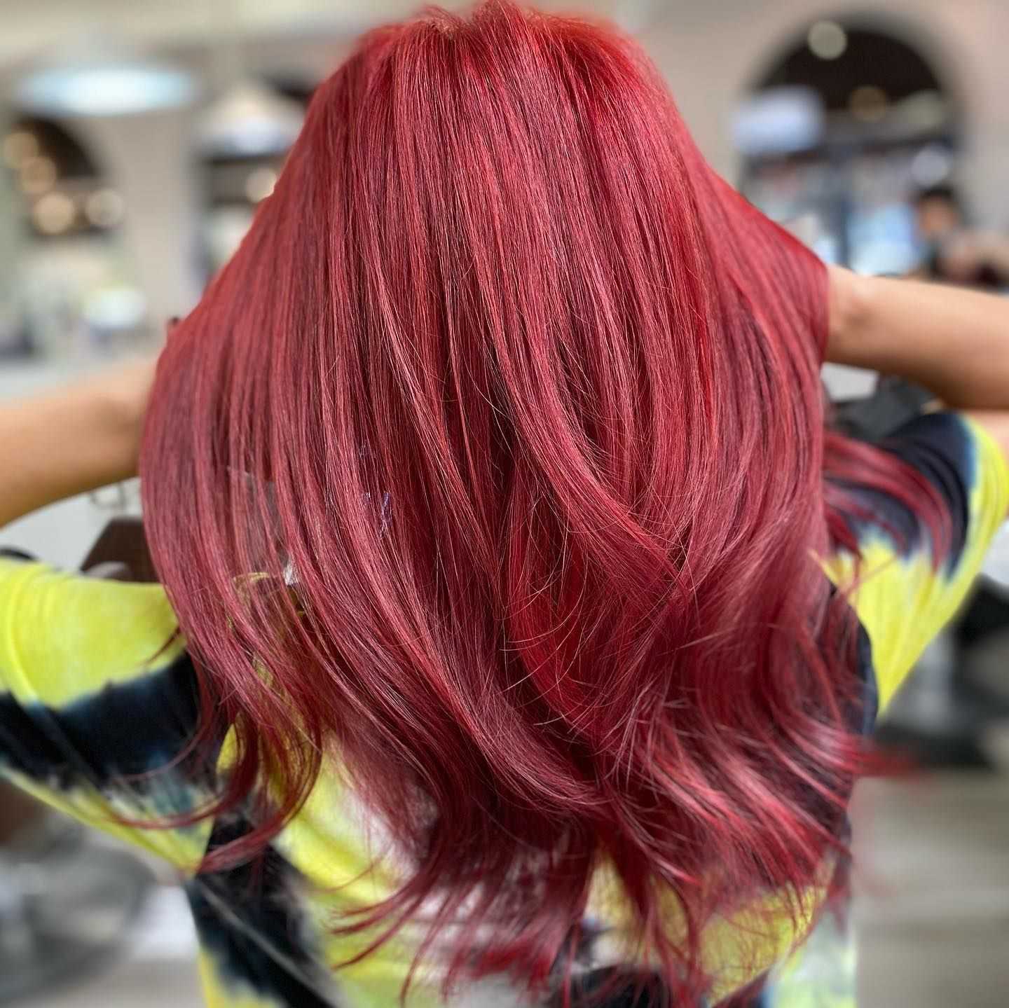Woman with long, vibrant red hair in a salon setting.